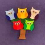5 differently colored owls on top of a tree- all made of felt.
